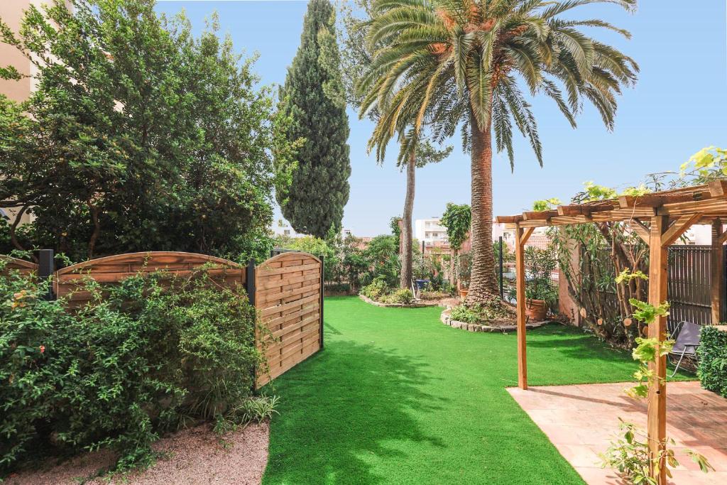 un jardin avec une clôture et une pelouse verdoyante dans l'établissement RARE-Superbe appt Suquet, jardin,6p,200m Croisette, à Cannes