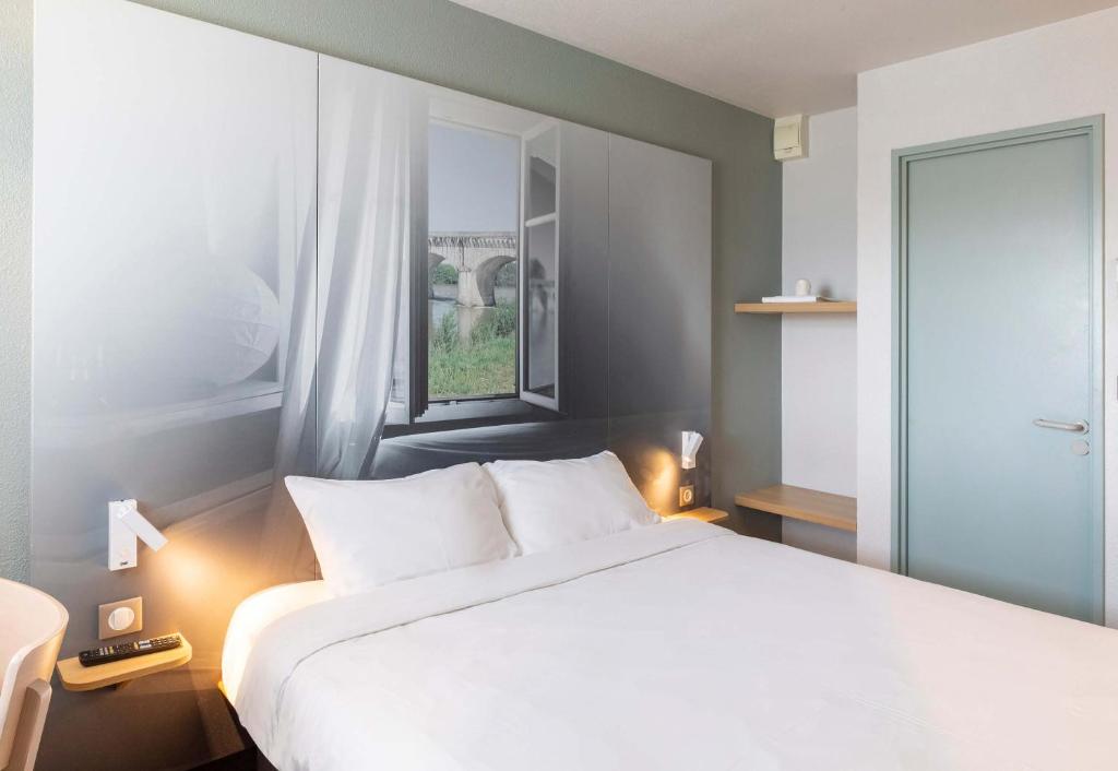a bedroom with a large white bed and a window at B&B HOTEL Agen in Agen