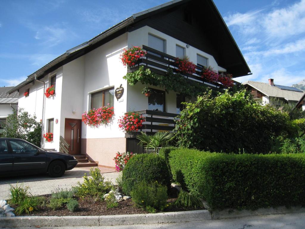 a white house with flowers on the side of it at Apartments and Rooms Tavcar in Bled