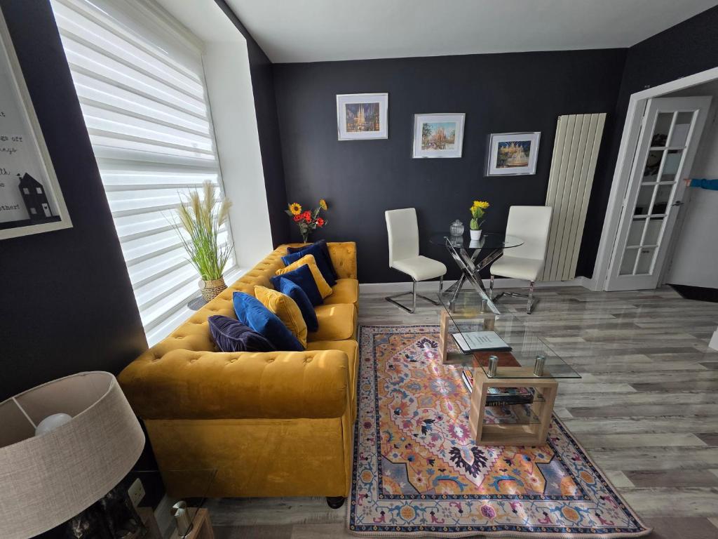 a living room with a yellow couch and a table at The Holiday 20 flat! outside LEZ in Aberdeen