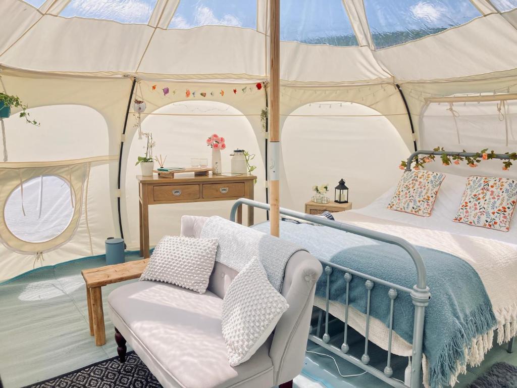a bedroom in a tent with a bed and a chair at Luxury Stargazing Glamping - Seren Hardd with Hot Tub in Llanidloes