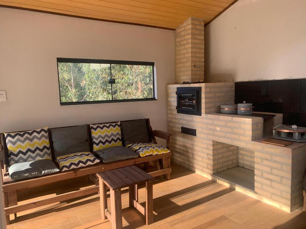 a living room with a couch and a brick fireplace at Refúgio Três Estações in Paty do Alferes