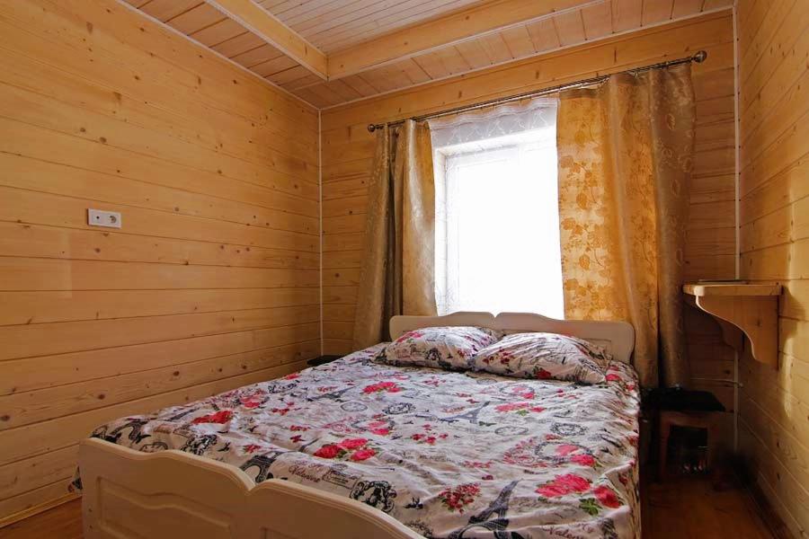 a bed in a wooden room with a window at Котедж 7я in Verkhovyna