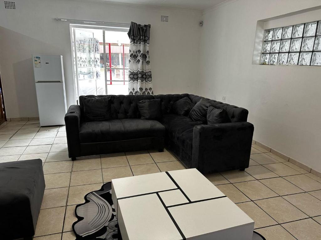 a living room with a black couch and a table at Modest Cottage in Germiston