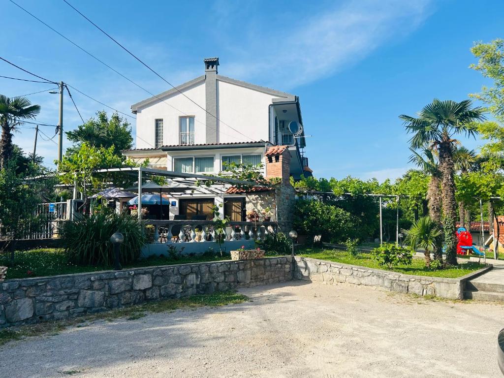 a large white house with a palm tree at Apartments & Rooms Ribarić in Lovran
