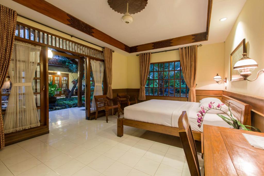 a bedroom with a bed and a dining room at Duta Garden Hotel in Yogyakarta