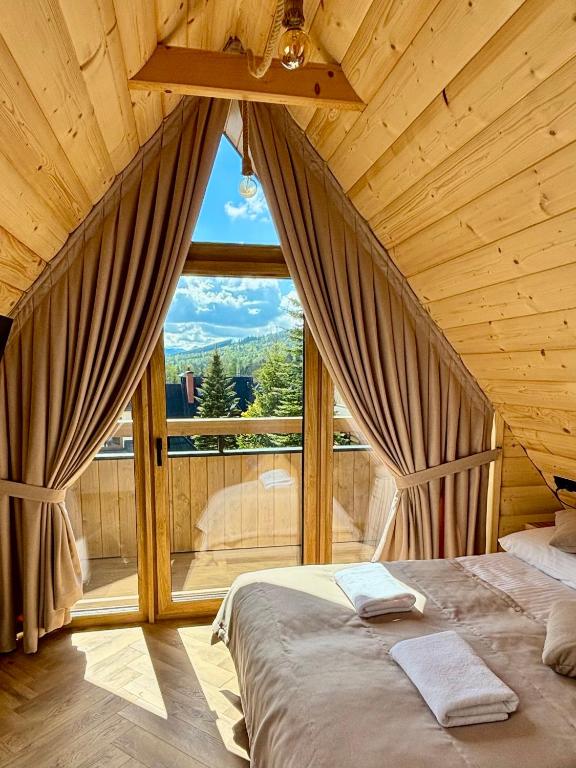 a bedroom with a bed and a large window at Zakątek Zakopane in Zakopane