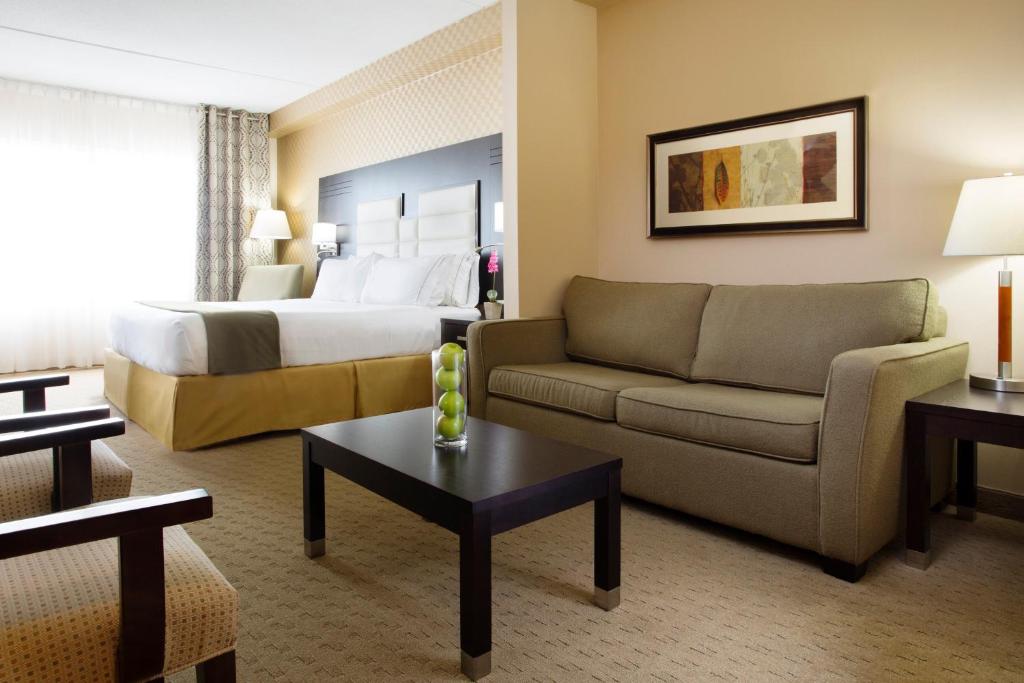 a hotel room with a bed and a couch at Holiday Inn Express & Suites Ottawa West - Nepean by IHG in Ottawa