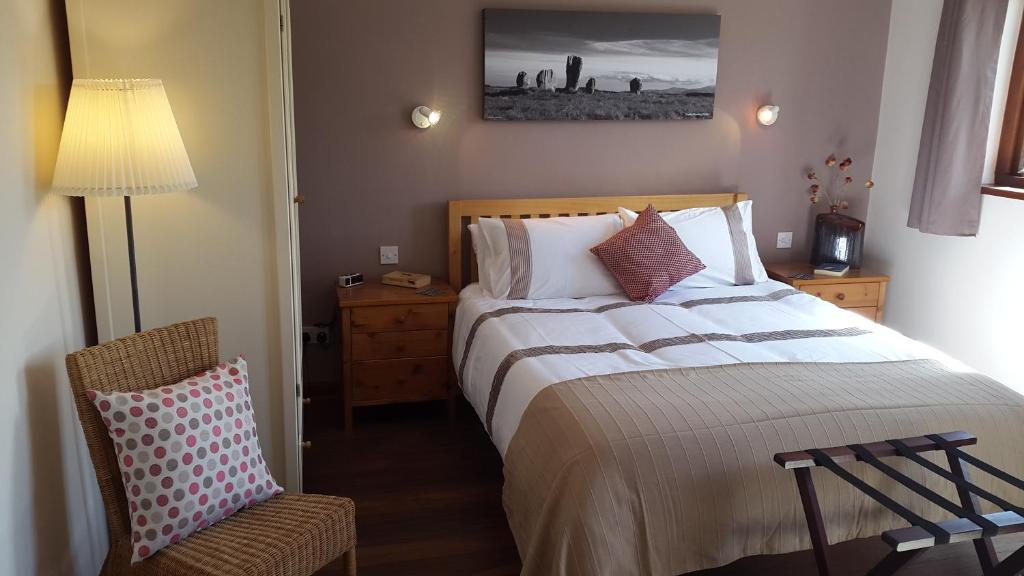 um quarto com uma cama grande e uma cadeira em Pantile Lodge em Milfield
