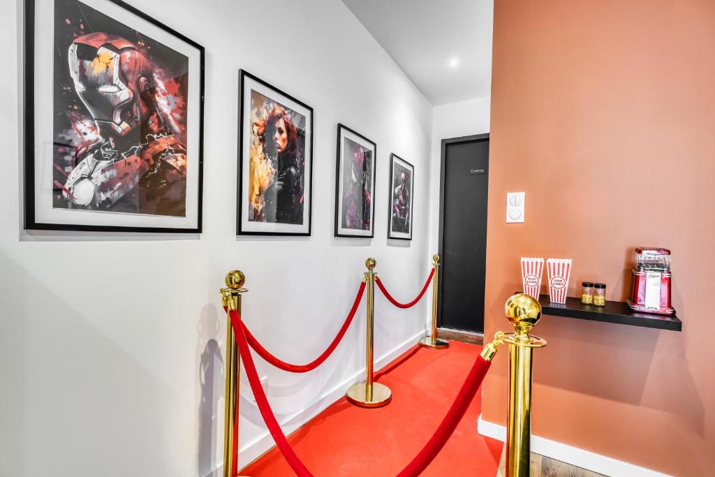 un tapis rouge dans un couloir avec des tableaux sur le mur dans l'établissement Cinéma & Expérience 4K - Popcorn OFFERT, à Saint-Étienne