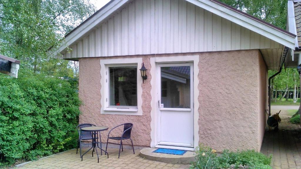 a small pink house with chairs and a table at Pärlebo in Mellbystrand
