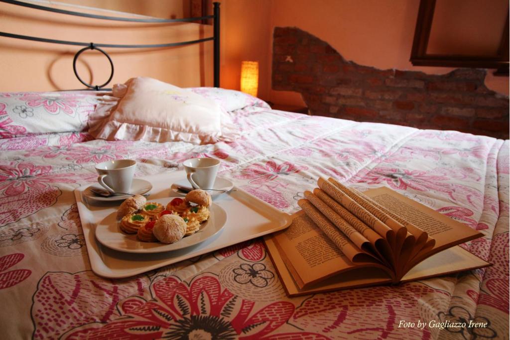 un plato de comida en una cama junto a un libro en B&B Le Palme d'Oro, en Grisignano di Zocco