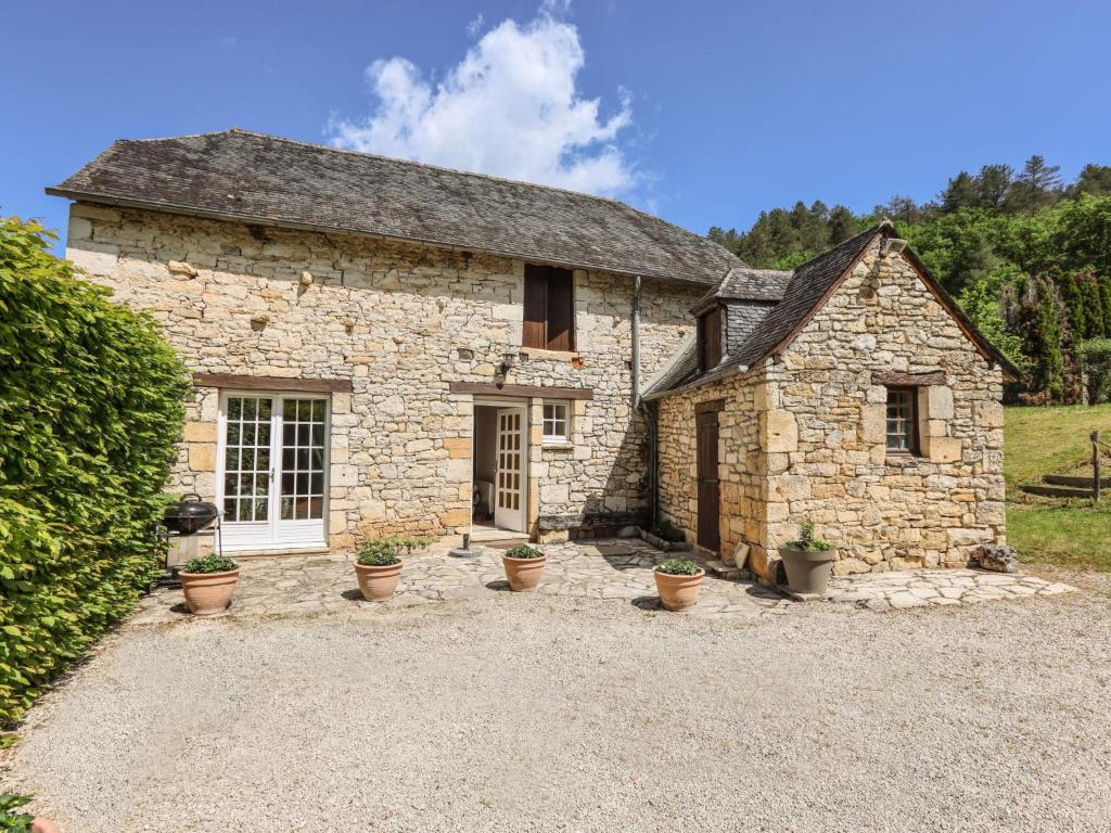 une maison en pierre avec des plantes en pot devant elle dans l'établissement Holiday Home La Colinoise by Interhome, à Coly
