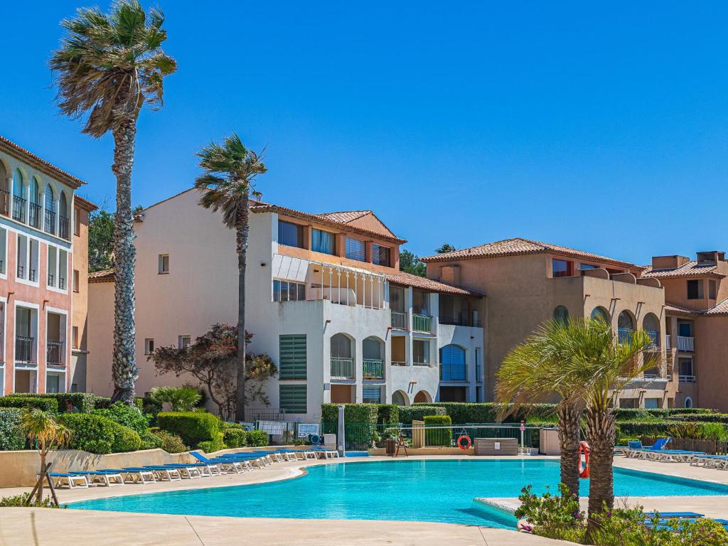 - une piscine bordée de palmiers et de bâtiments dans l'établissement Apartment Les Rivages de Coudoulière-8 by Interhome, à Six-Fours-les-Plages