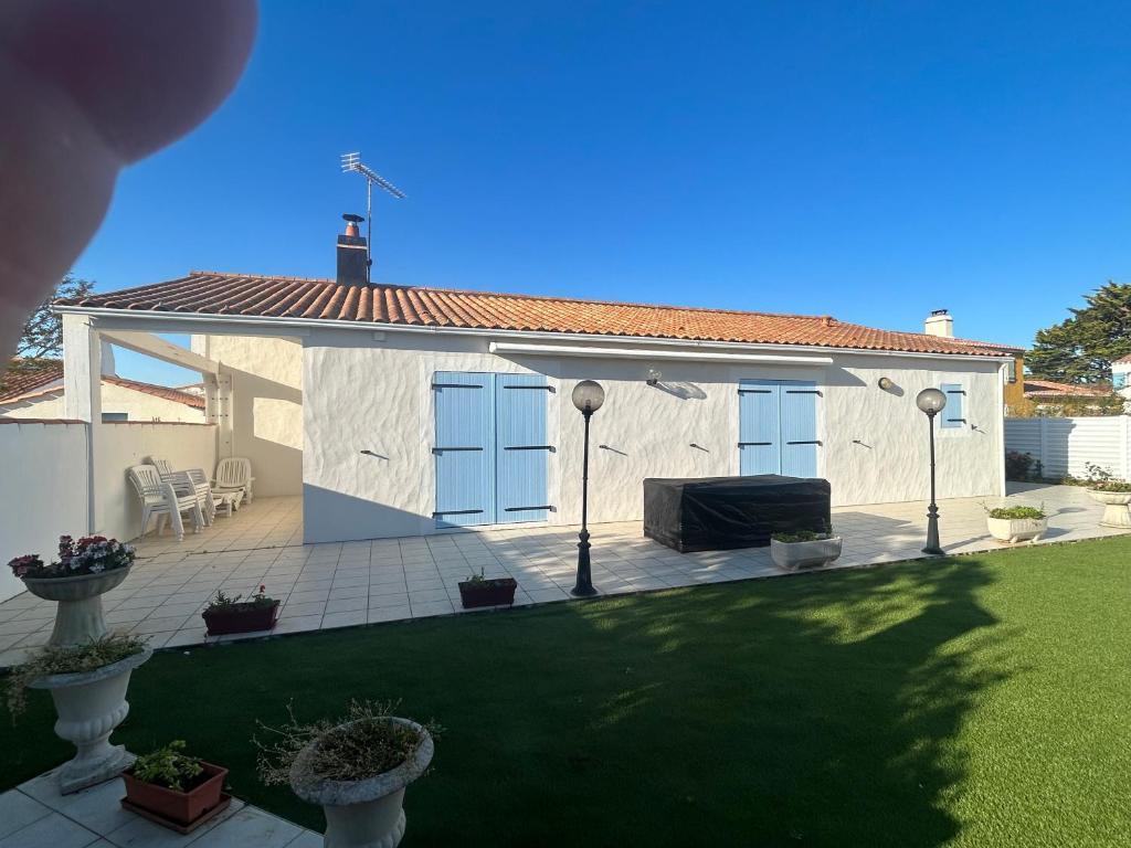 une maison blanche avec un toit et une terrasse dans l'établissement Maison Noirmoutier près du bois de la Chaise, à Noirmoutier-en-l'lle