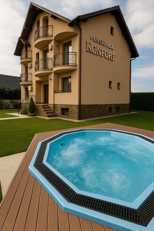 a large swimming pool on a deck in front of a building at Pensiunea Konfort in Baile Felix