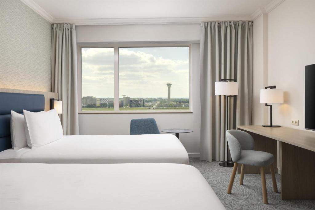 a hotel room with two beds and a window at Hilton Paris Charles De Gaulle Airport in Roissy-en-France