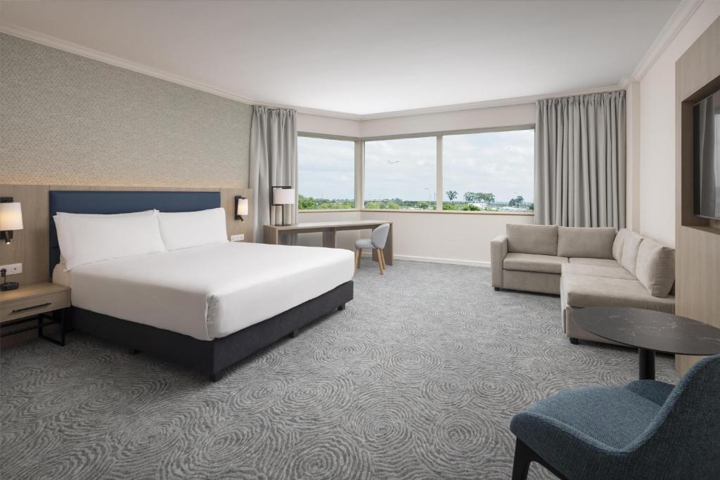 a hotel room with a bed and a couch at Hilton Paris Charles De Gaulle Airport in Roissy-en-France
