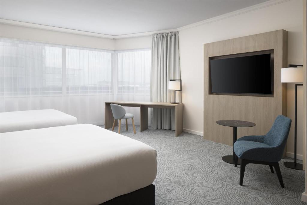 a hotel room with a bed and a desk and a tv at Hilton Paris Charles De Gaulle Airport in Roissy-en-France