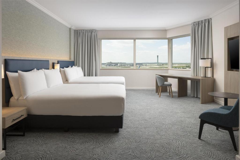 a hotel room with a large bed and a desk at Hilton Paris Charles De Gaulle Airport in Roissy-en-France