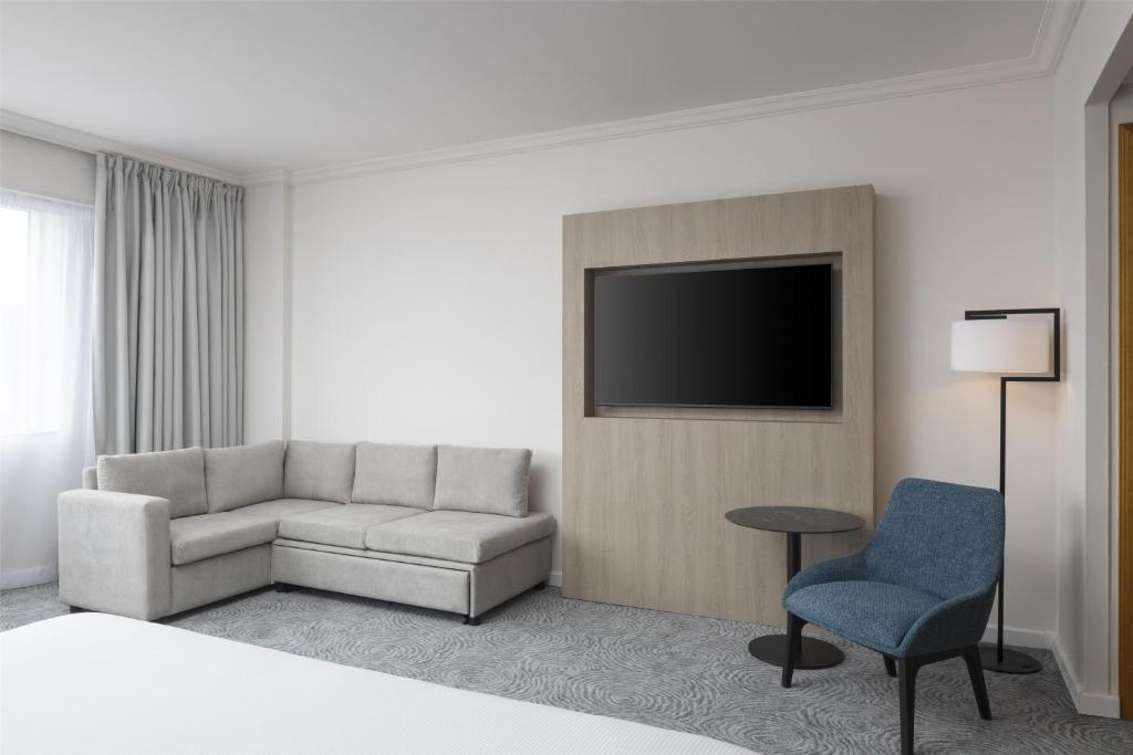 a living room with a couch and a tv at Hilton Paris Charles De Gaulle Airport in Roissy-en-France
