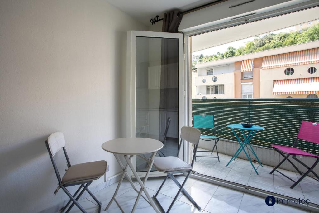 d'un balcon avec des chaises, une table et une fenêtre. dans l'établissement Air-conditioned studio district Bornala, à Nice