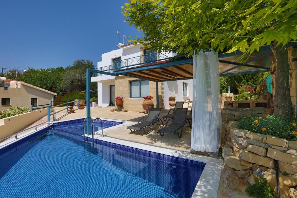 a swimming pool in front of a house at Julipapas Gardens in Paphos