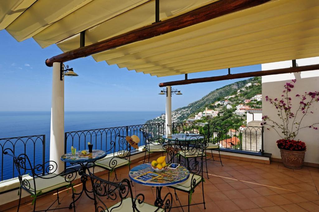 balcone con tavoli, sedie e vista sull'oceano di La Casa Del Melograno a Furore