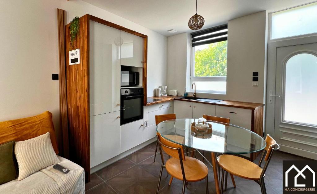 une cuisine avec une table en verre et des chaises dans une pièce dans l'établissement Au Vallon du Bonheur - Maison 4pers avec Cour, à Boulogne-sur-Mer