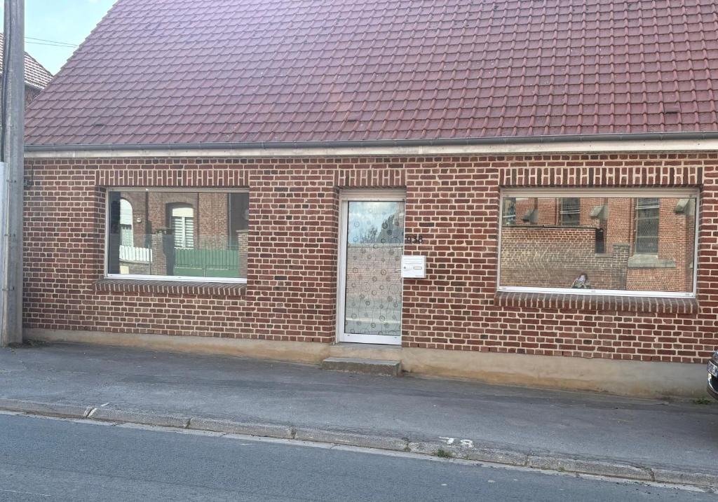 a brick building with two windows and a red roof at Charmante maison de campagne in Gouzeaucourt