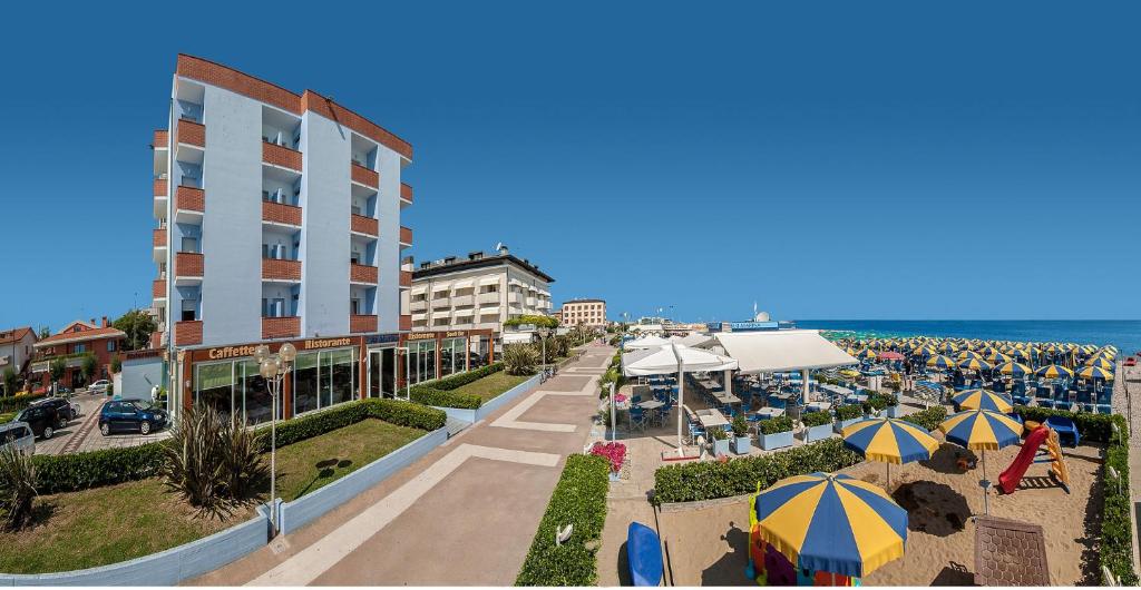 un complejo con mesas y sombrillas y el océano en Hotel Marina, en Fano