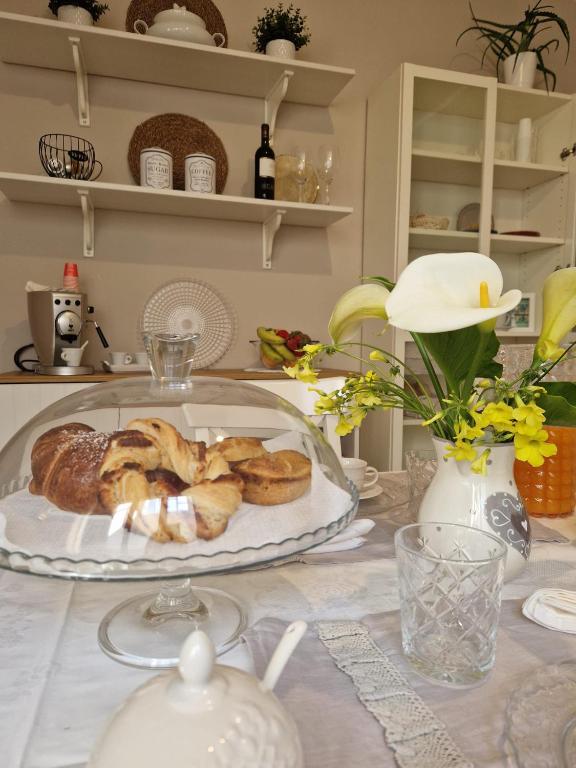 a table with a plate of bread and a vase with flowers at A Casa da Maria in Melissano