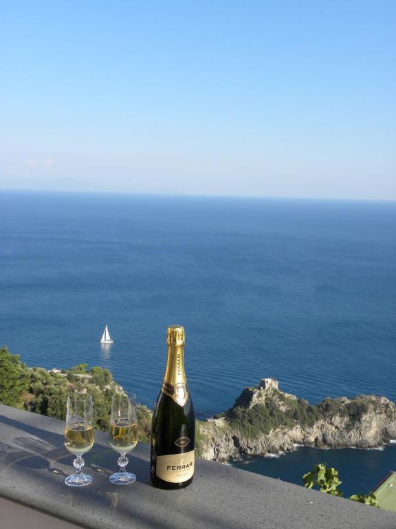 a bottle of wine and three wine glasses on a ledge at Holiday House ROSANNA in Conca dei Marini