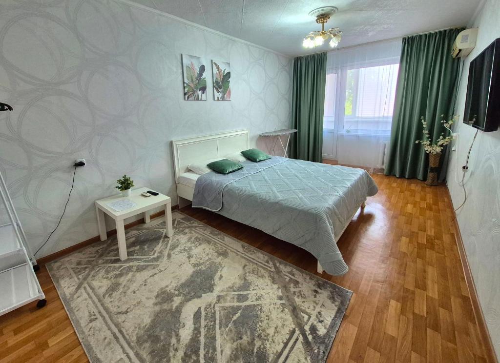 a bedroom with a bed and a table in it at 1 к квартира в Центре Мухита д 128 in Uralsk