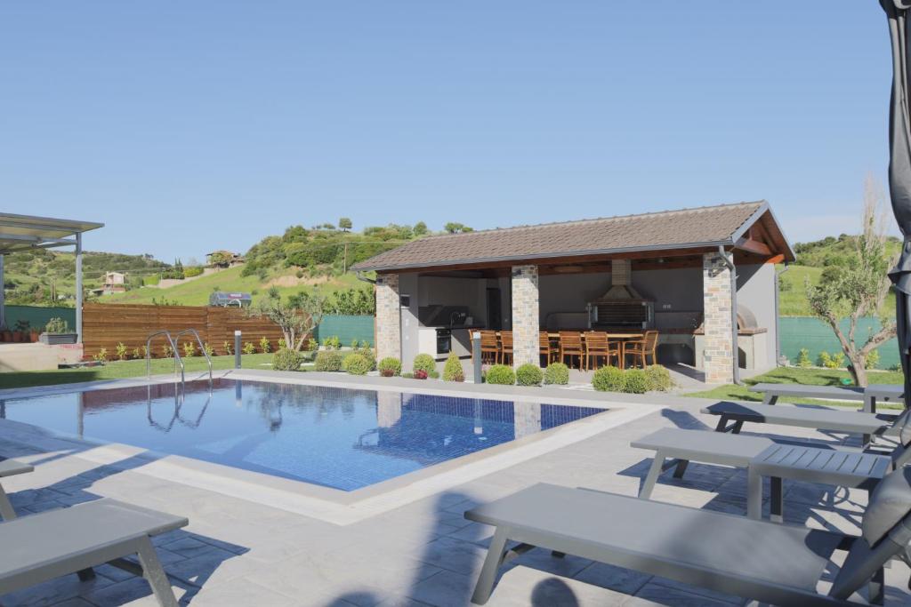 a swimming pool with chairs and a house at Villa Bengu luxury villa in Nikiti