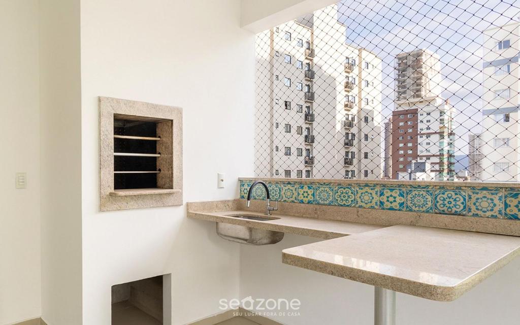 a bathroom with two sinks and a window at Apto 450m da praia c/ churrasq. e 3 suítes TAH0602 in Meia Praia