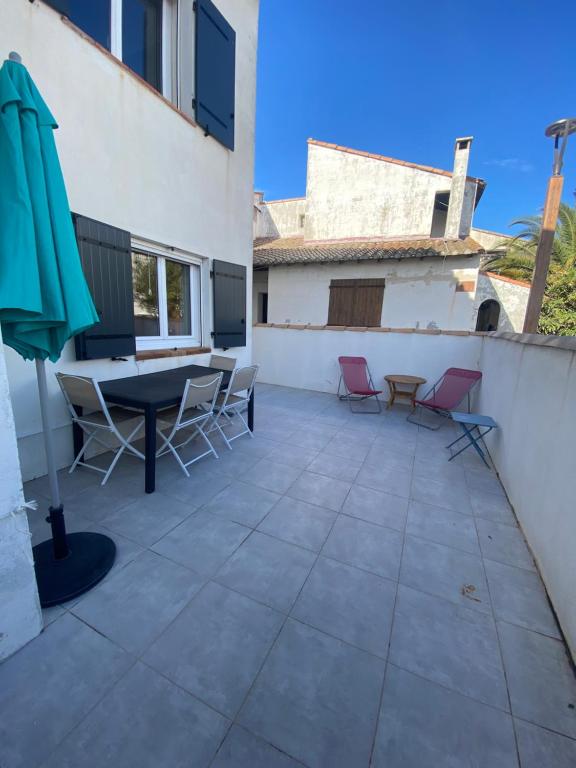 un patio avec une table, des chaises et un parasol dans l'établissement Lou pastre, à Saintes-Maries-de-la-Mer