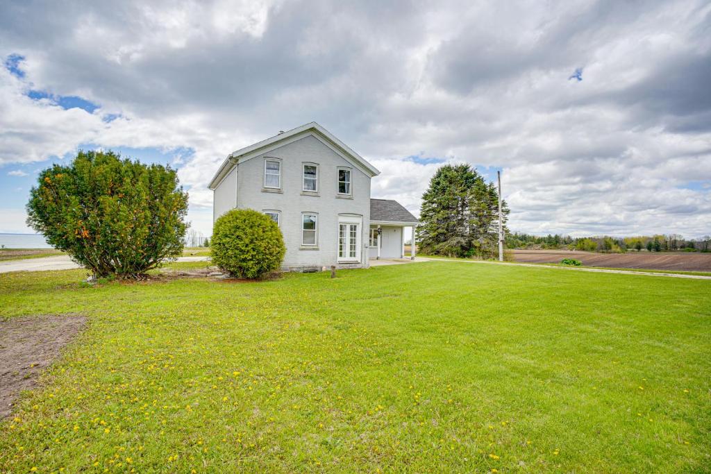 a white house on a large grassy field at Waterfront Lake Michigan Home on 15 Acres! in Manitowoc