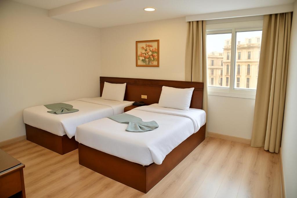 ein Hotelzimmer mit zwei Betten und einem Fenster in der Unterkunft Miramar Green Talaat harb in Kairo