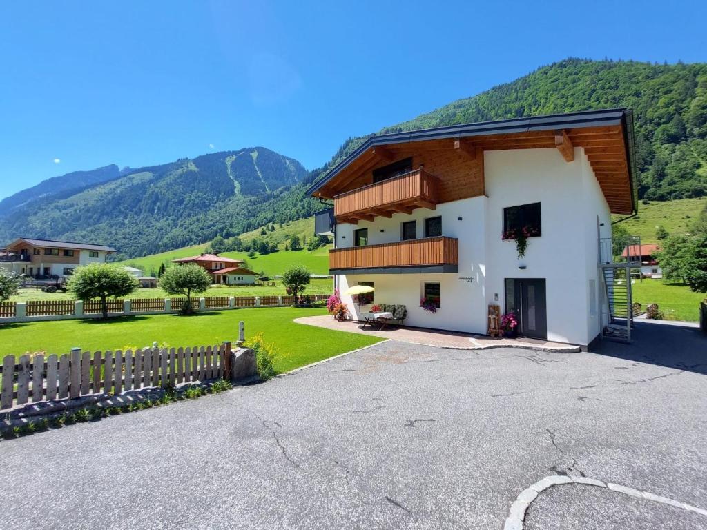 a white house with a fence and mountains in the background at Apartment Dankl by Interhome in Fusch an der Glocknerstraße