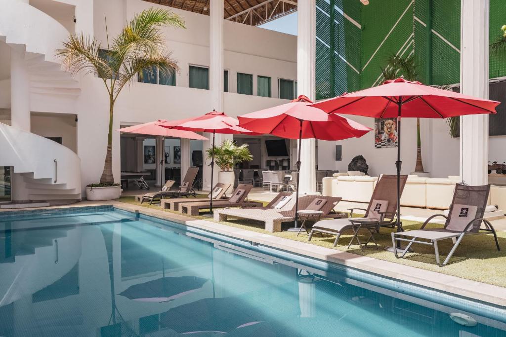 ein Swimmingpool mit Stühlen und Sonnenschirmen neben einem Gebäude in der Unterkunft Casa Ferlioni in Temixco