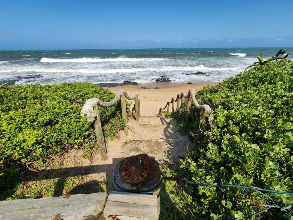 a stairway to the beach with the ocean in the background at Port Royale Beach Cottage in Shelly Beach