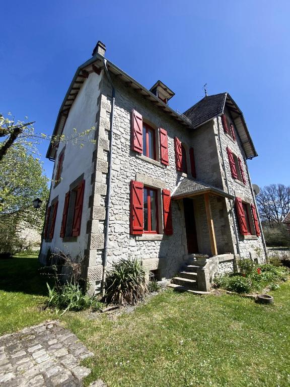 une vieille maison avec volets rouges sur une pelouse dans l'établissement Maison de famille en Haute Corrèze, à Maussac