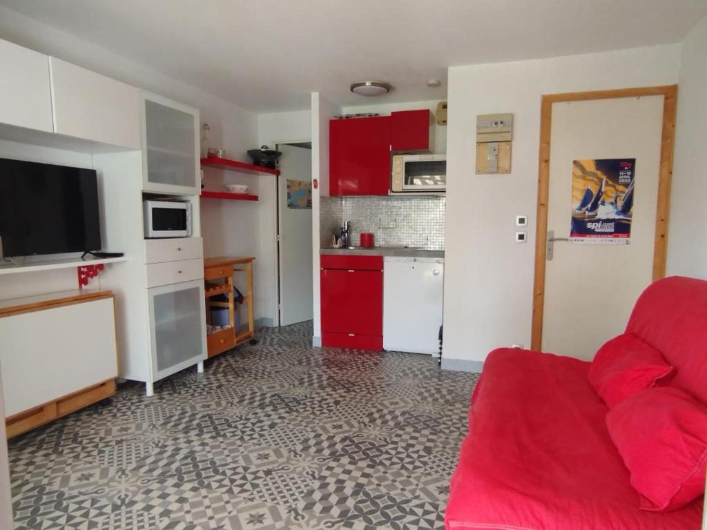 een woonkamer met een rode bank en een keuken bij Studio carnac in Carnac