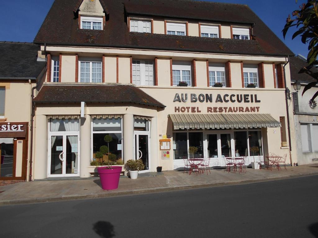 a building with tables and chairs in front of it at Au Bon Accueil in Juvigny-sous-Andaine