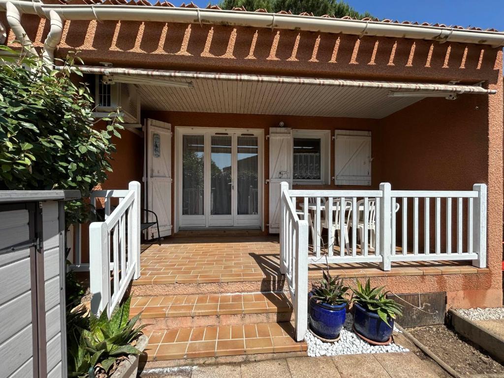 un porche de una casa con una valla blanca en Mazet climatisé avec piscine & tennis Résidence calme proche Lavandou, en Bormes-les-Mimosas