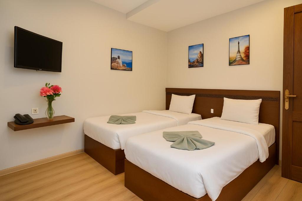 twee bedden in een kamer met een tv aan de muur bij Miramar Green Talaat harb in Caïro