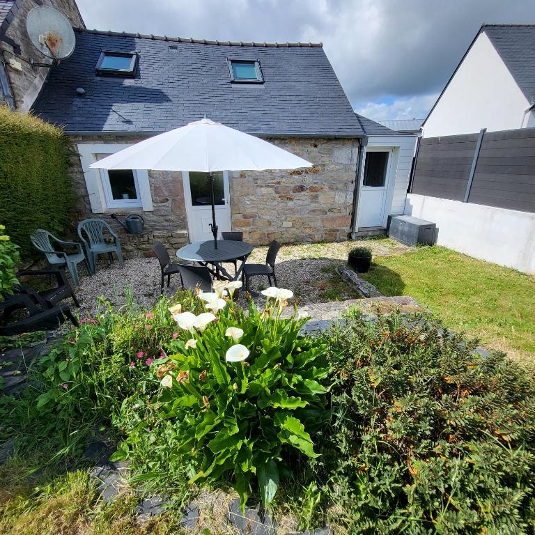 une terrasse avec un parasol, des chaises et des fleurs dans l'établissement La maison d'étape, à Saint-Évarzec