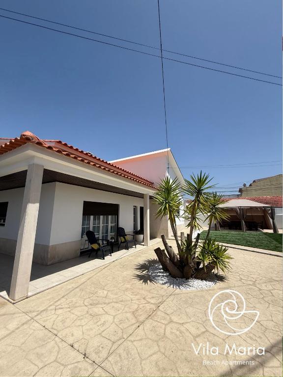 a house with a patio and palm trees in it at Vila Maria Beach Apartments in Pataias