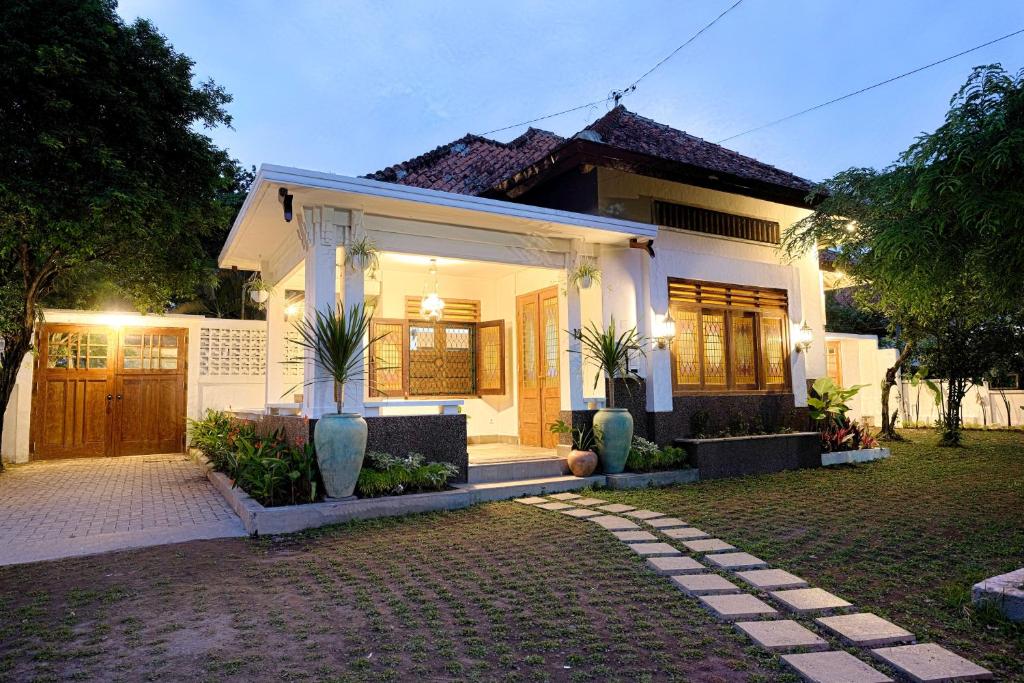 a white house with a gate and a driveway at Entire Heritage Villa Family friendly in the Center of Yogya with Swimming Pool - Up to 9 people in Yogyakarta